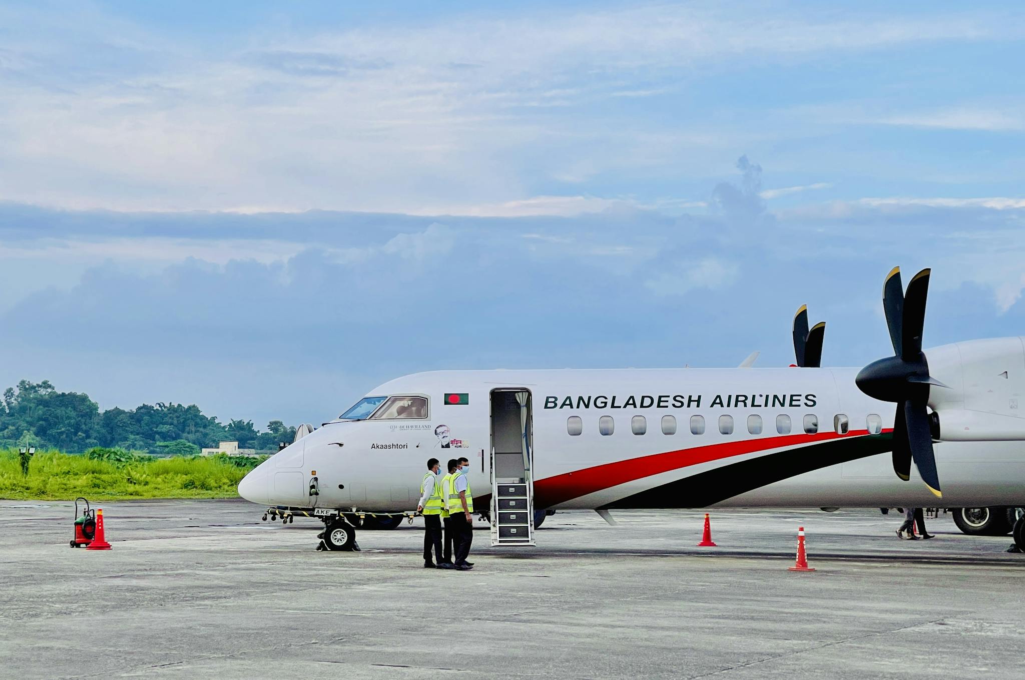 Bangladesh Airlines plane on Dhaka tarmac with crew preparing for departure.