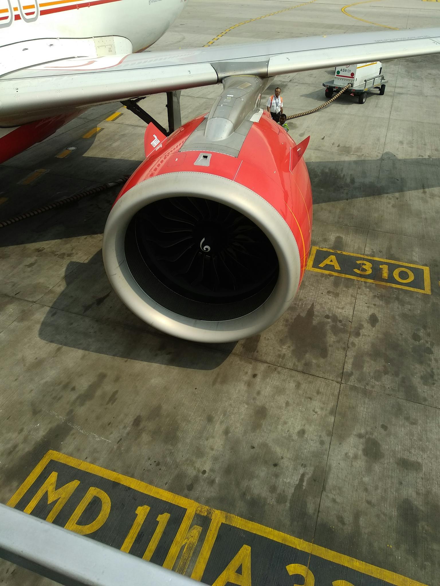 Detailed view of an airplane engine on the tarmac at an airport in Delhi, India.