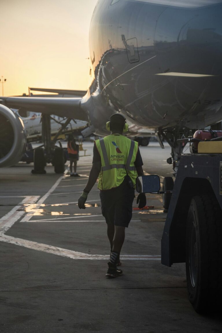 Ground crew member at airport during sunset, ensuring aircraft readiness.