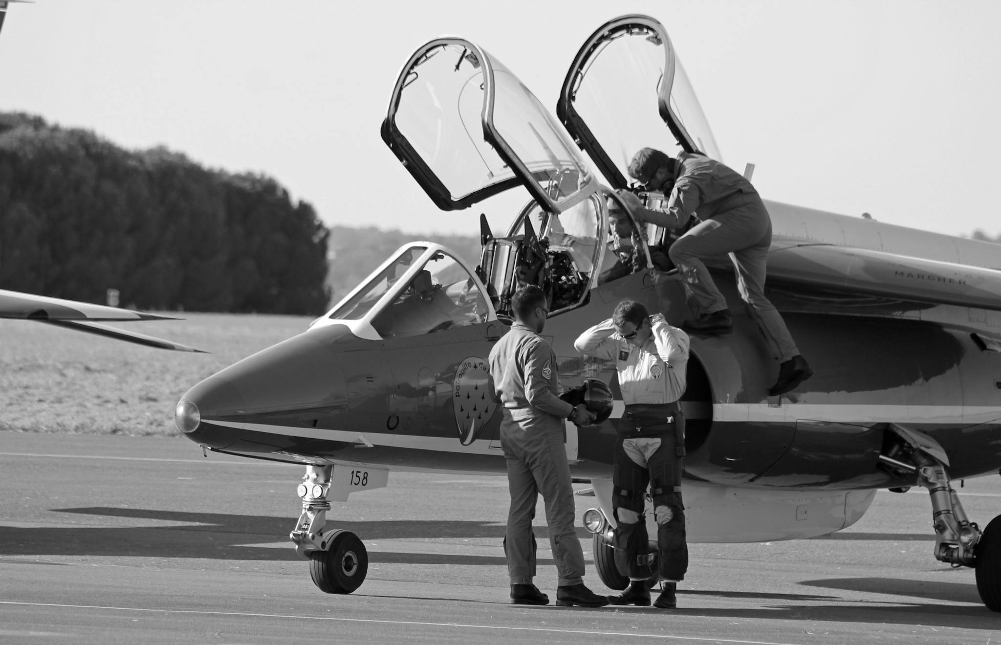 Jet fighter with crew preparing at airfield. Black and white image highlighting teamwork and aviation.
