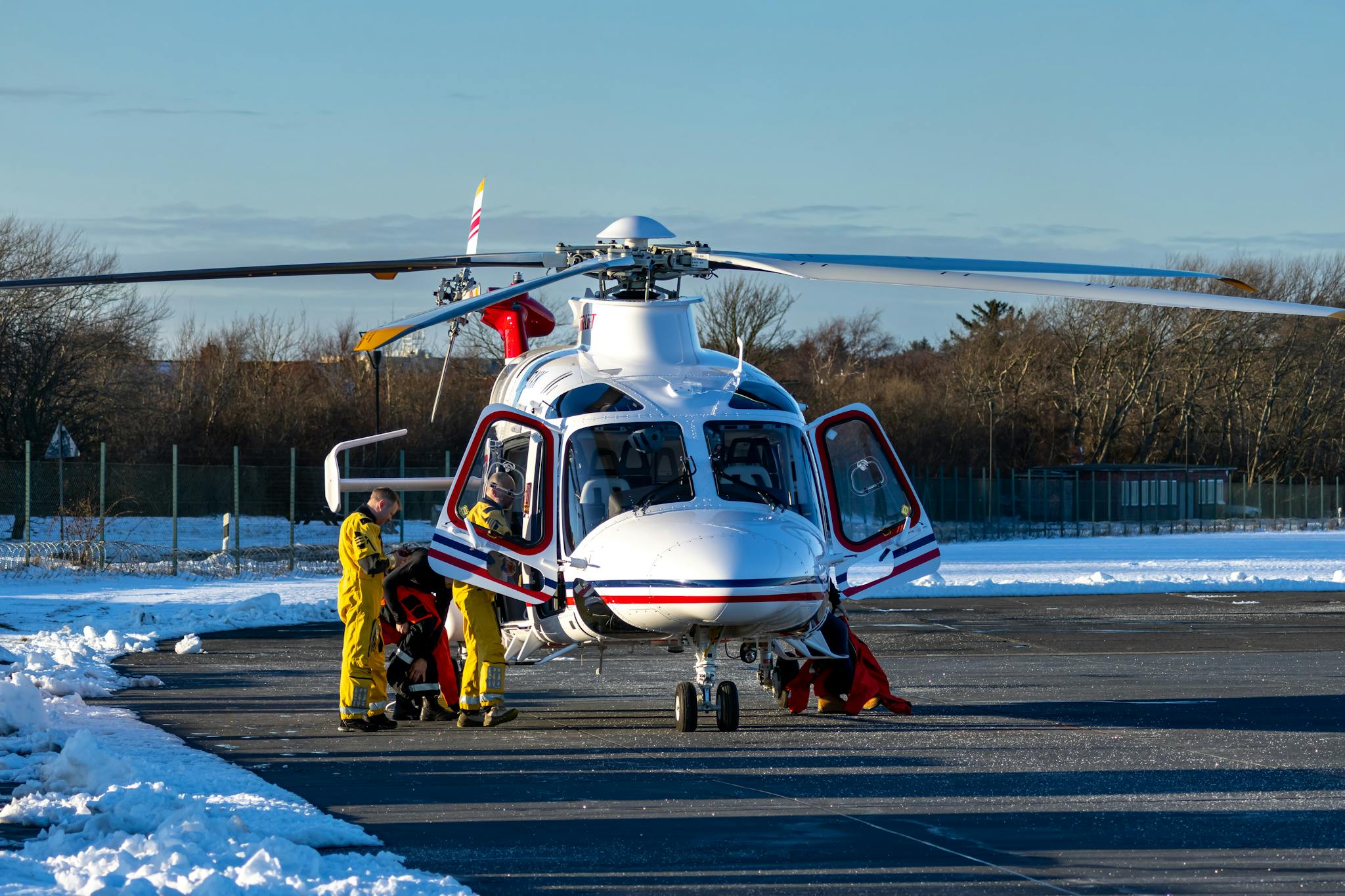 Emergency crew with helicopter on a snowy runway performing a rescue operation in winter.