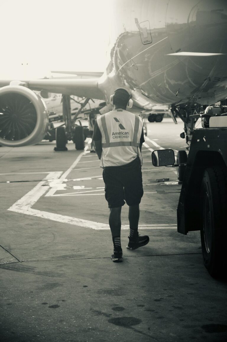 Ground crew member in safety vest walks near airplane at airport terminal